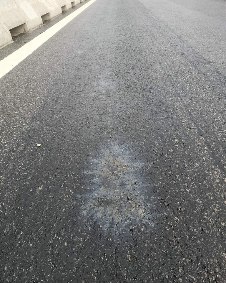 Bề mặt của đường tại vị trí này vẫn còn một lớp hóa chất lạ màu đen bám lại. Hình dạng vị trí bị bong lớp nhựa đường cho thấy hóa chất bị đổ từ trên xuống.